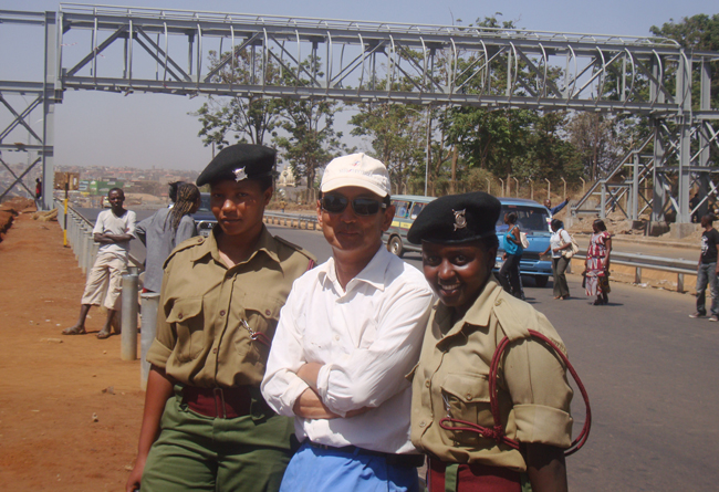 2-王泉勇与肯尼亚当地警察合影（身后是他参与吊装的钢结构天桥）.jpg